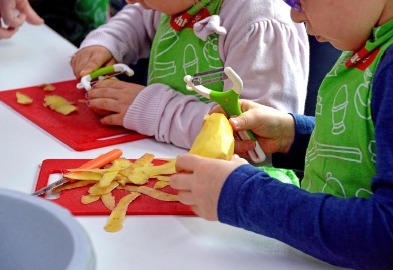Kindergartenkinder beim Kartoffelschälen
