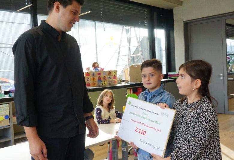 Zwei Schüler:innen übergeben die Spende an das Jugendland