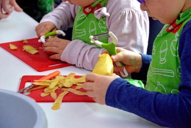 Kindergartenkinder beim Kartoffelschälen im Kochkurs