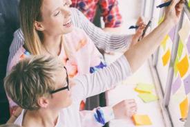 Gruppe Frauen bekleben Fensterscheibe mit postits von innen